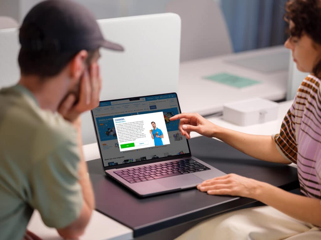 Two people looking at the Coolblue website on a laptop. The cookie banner is shown.